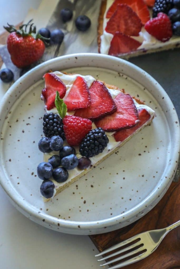 A slice of the cookie fruit pizza on a plate. 