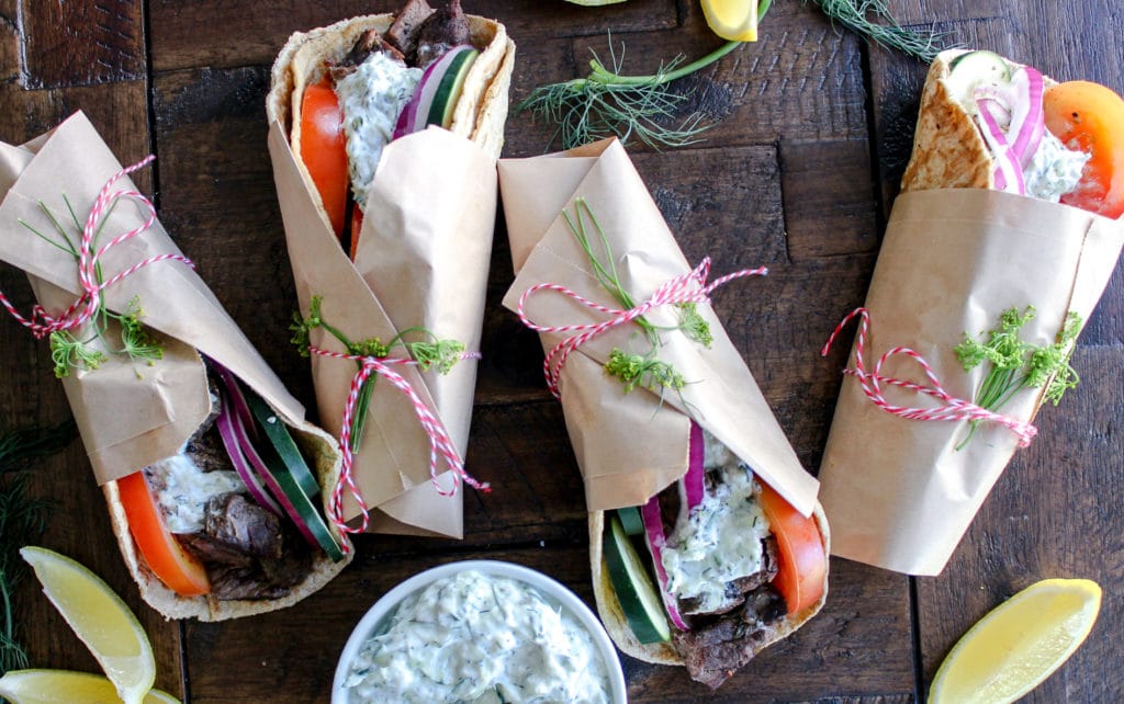 A table topped with different types of food, with Flatbread and Gyro