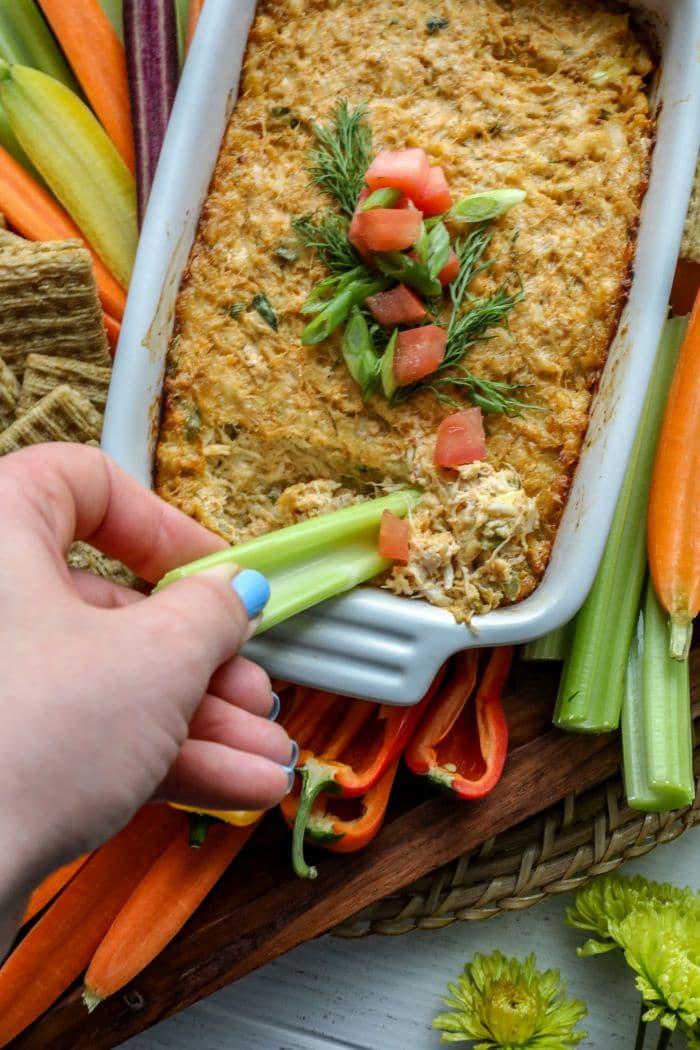 Easy Smoked Crab Dip on a piece of celery held by a hand