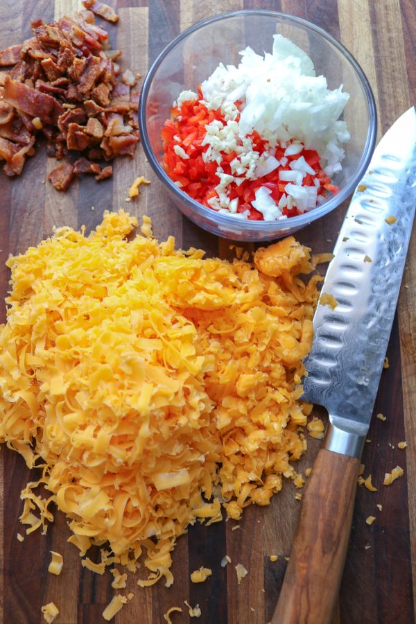 Shredded cheese on a cutting board next to a knife