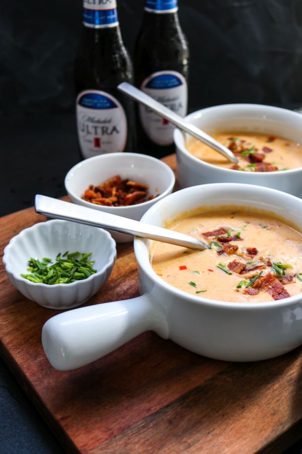 Michelob ultra low carb beer cheese soup in white bowls with spoons