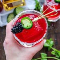 A hand holding a low carb blackberry jalapeno margarita