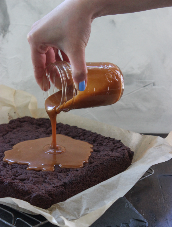Keto caramel being poured over keto brownies.