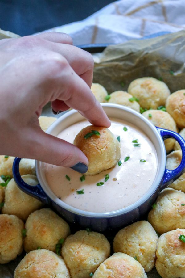 keto cheddar biscuit bomb being dipped in keto beer cheese sauce