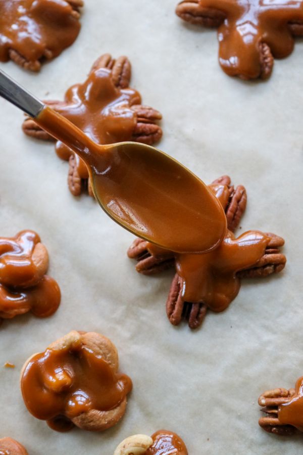Spooning keto caramel over nuts.