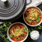 Two bowls of beef chili and a large black pot