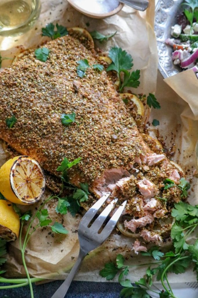 Pistachio salmon on a platter being cut with a fork