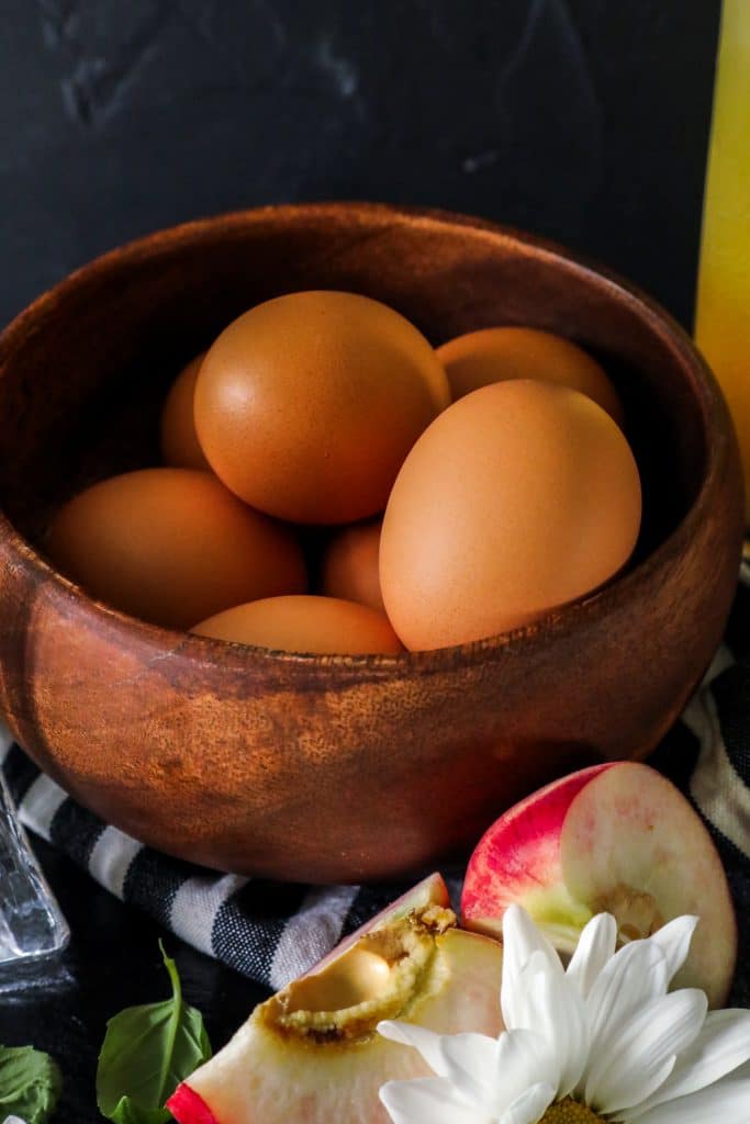 A bowl of eggs and a peach. 