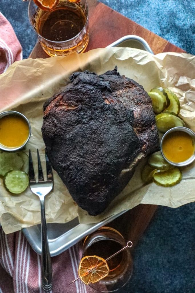 Completed and smoked pork shoulder on a tray resting.