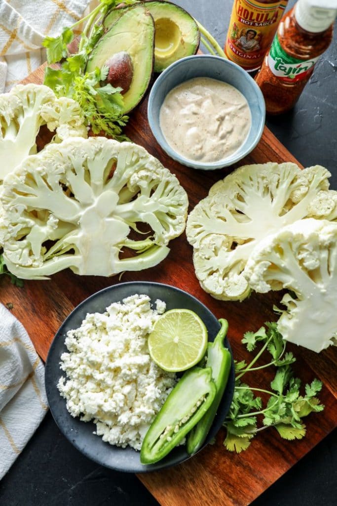 Raw sliced cauliflower steaks on a cutting board.