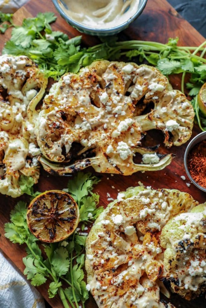 A close up of garnished elote cauliflower steaks. 