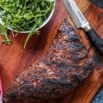 A whole tri tip on the cutting board with a knife.