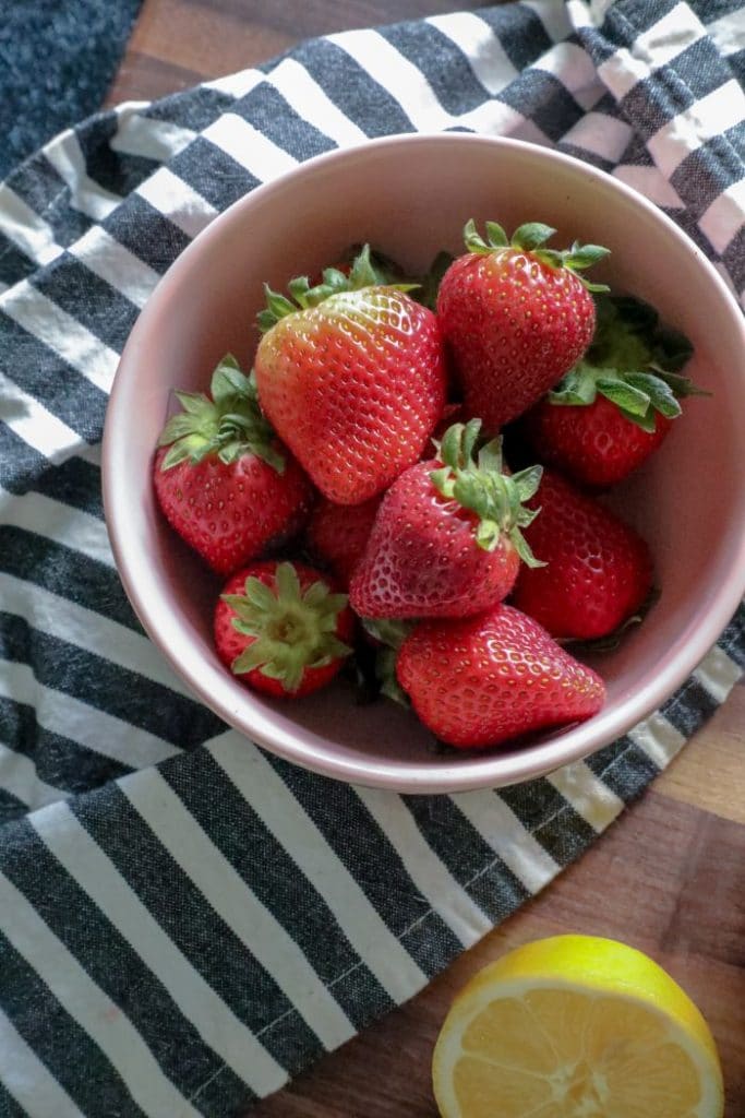 A bowl of fruit on a plate, with Strawberry