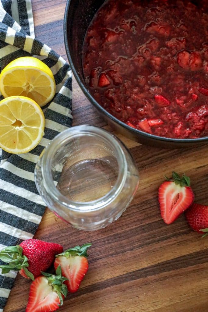 Strawberry sauce and an empty jar on a table. 