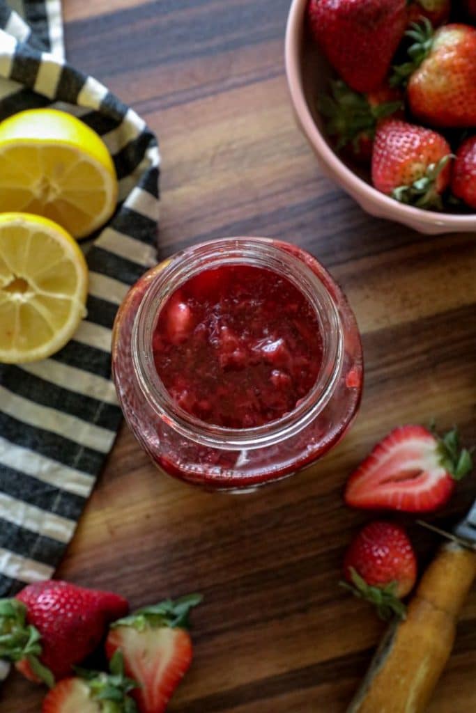 A bowl of fruit sitting on top of a wooden table, with Strawberry