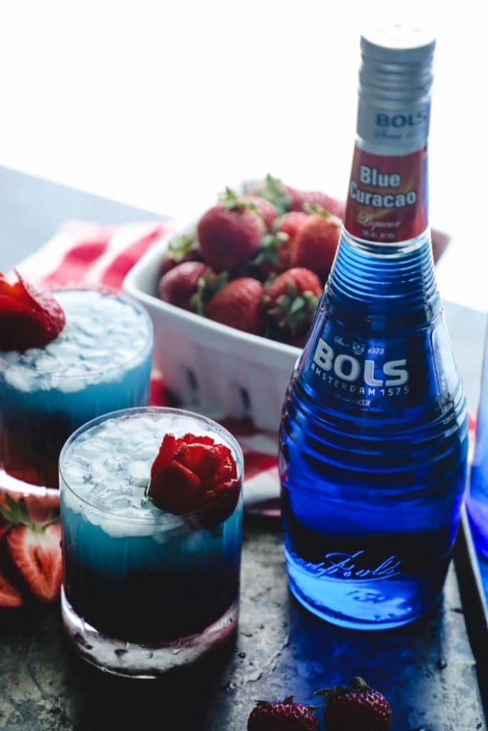 The cocktail next to a bottle of Blue Curacao