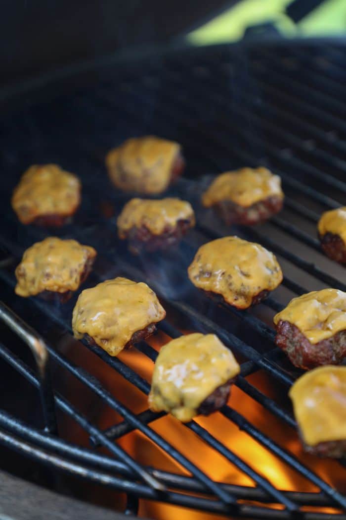 Mini burger patties on the grill with cheese