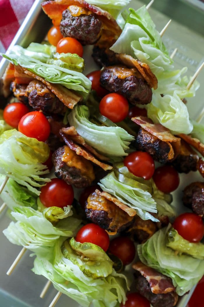 A plate is filled with bacon cheeseburger kebabs.