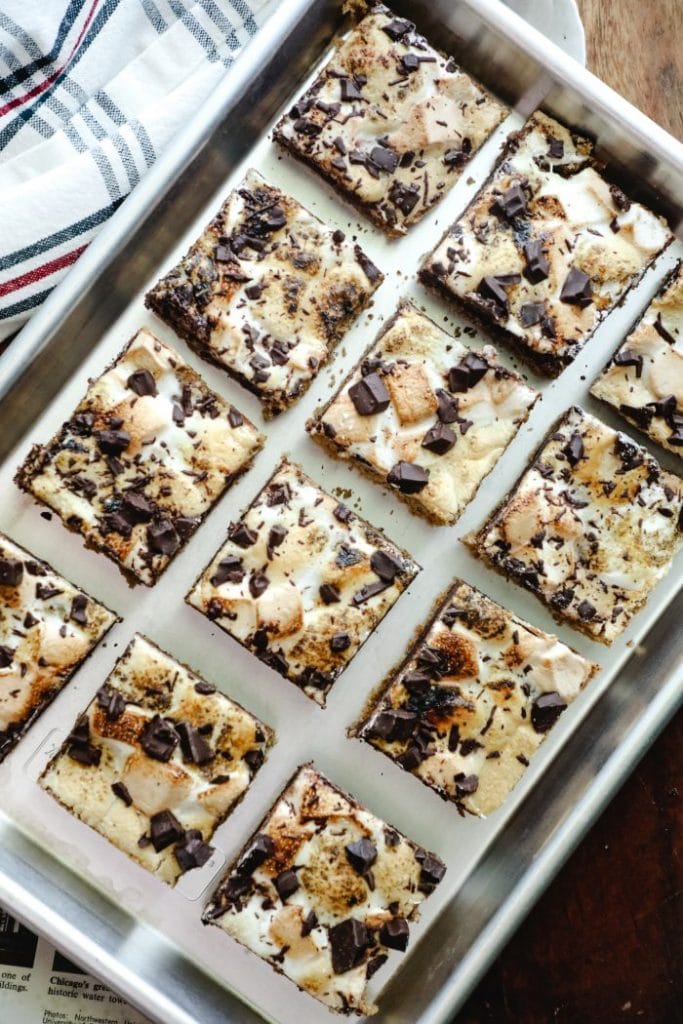 Angled sheet pan with the cut smores bars land a towel underneath
