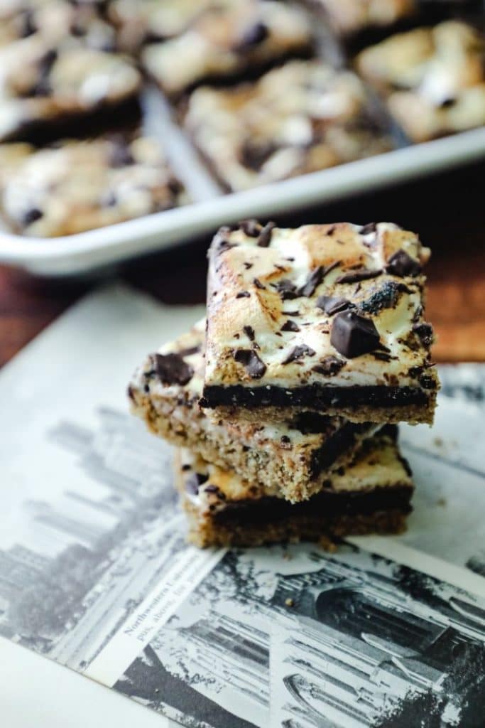 Three keto smores bars stacked up with newspaper underneath