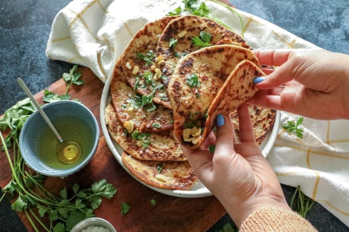 A picture of hands holding a folded flatbread to show it's durability and bend-ability