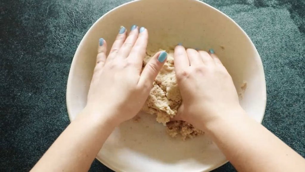 hands kneading the flatbread dough in a bowl