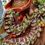 Gravy boat of mole sauce with a platter of layered sliced pork tenderloin with mole sauce over the top