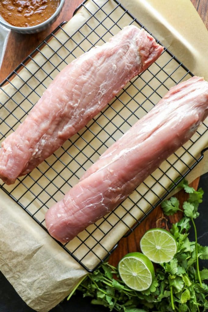 Two raw pork tenderloins on a baking sheet.