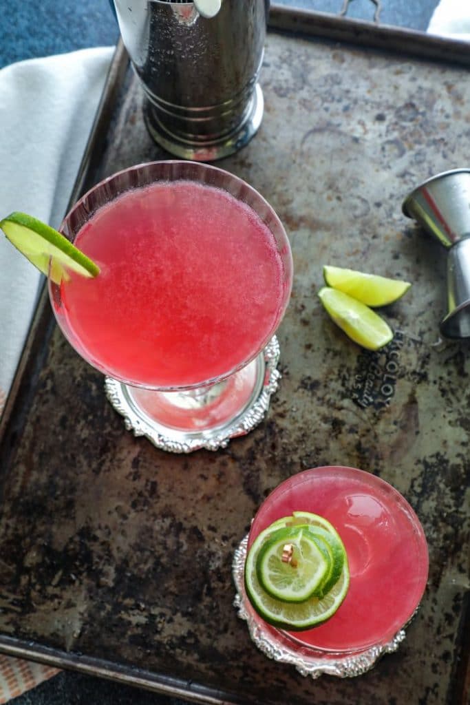 Top view of two cosmo cocktails on a metal tray.