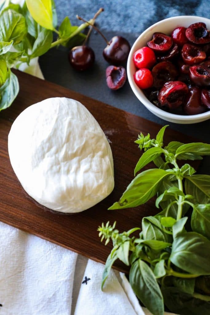 Ball of burrata cheese sitting on a wood cedar plank.