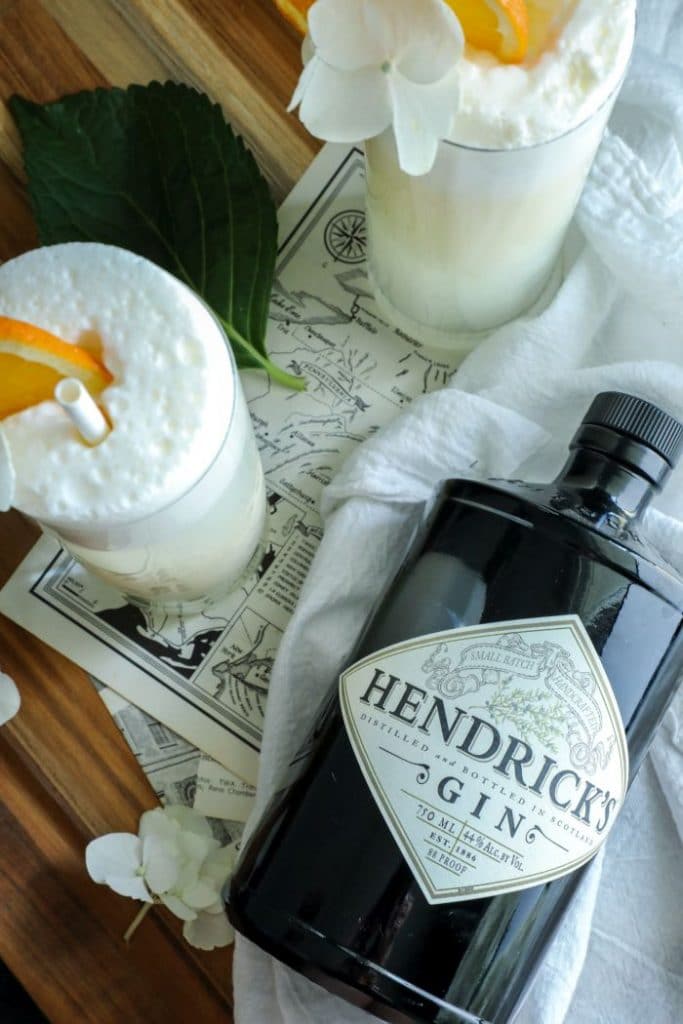 A bottle of Hendricks Gin on a white towel with two Two Keto Creamsicle Gin Fizz cocktails.