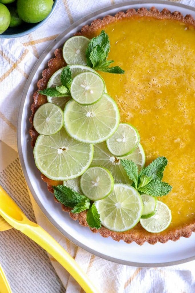 Close up of the keto key lime tart decorated with limes. 