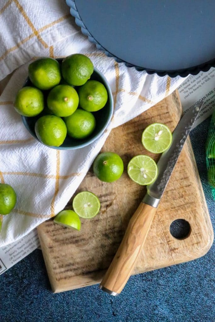 Key limes on a cutting board with a knife. 