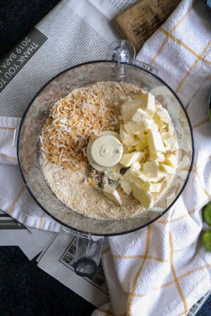 Dry ingredients for keto shortbread and toasted coconut inside the food processor. 