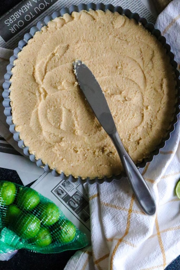 The keto shortbread crust patted into the tart pan with a knife.