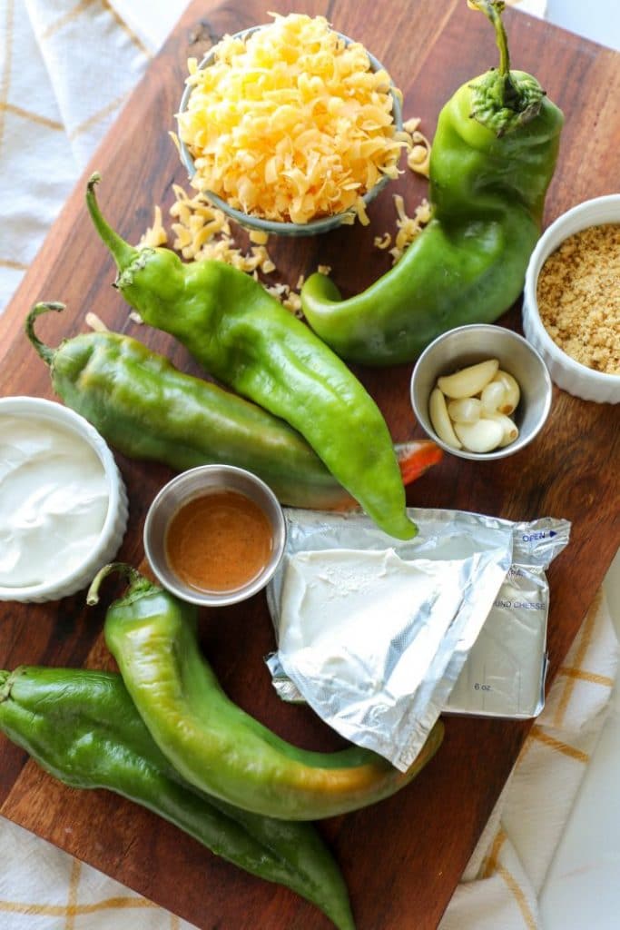 Hatch chili peppers with cheese on a cutting board.