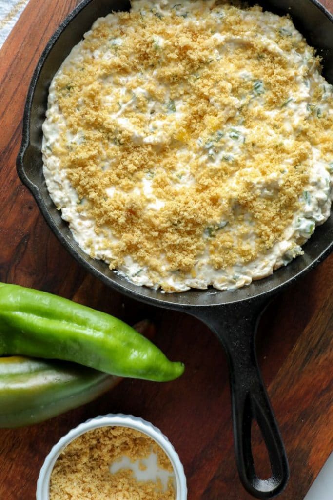 Smoked Hatch Chili Pepper Dip topped with pork rind crumbs in a cast iron pan. 