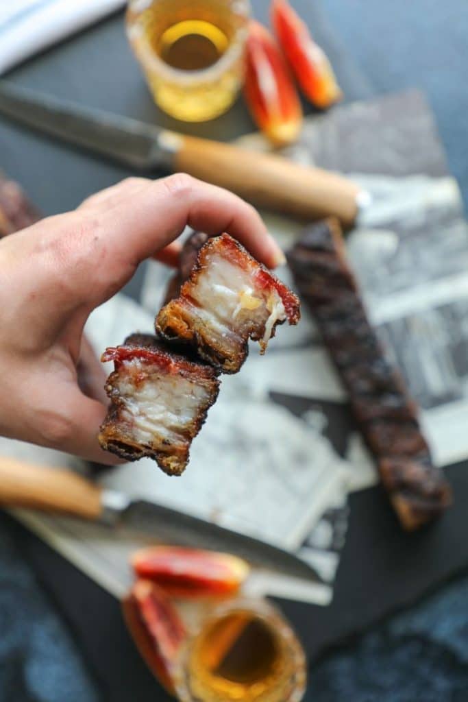 Hot and fast smoked pork belly being held in a hand. 