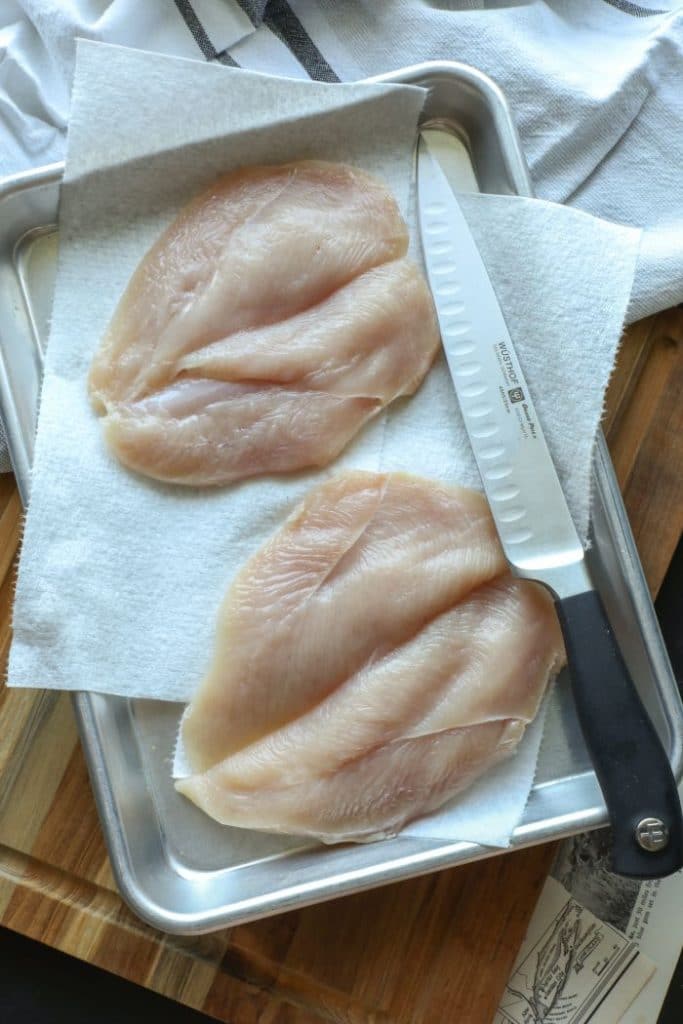Two butterflied boneless skinless chicken breast on a tray.