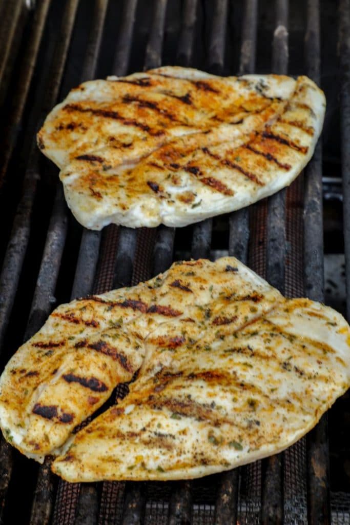 Butterflied chicken breasts over direct heat on a gas grill.