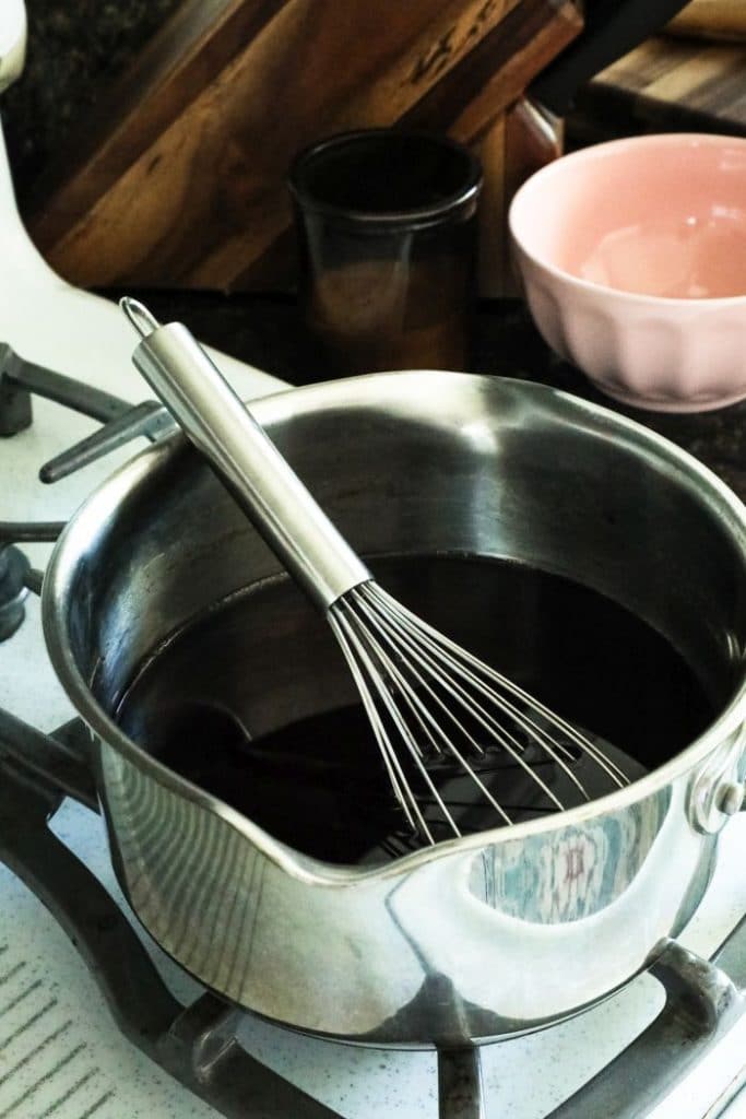 A tablespoon of Keto Grenadine Cocktail Syrup in a pot on the stove.