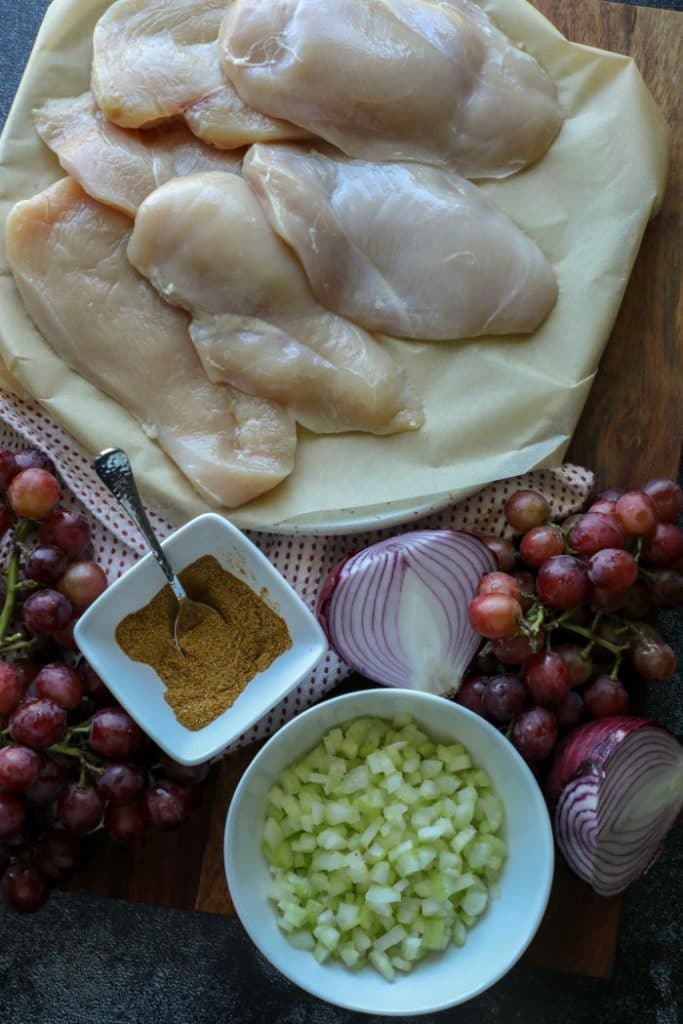 Curry chicken salad ingredients on a wood cutting board.