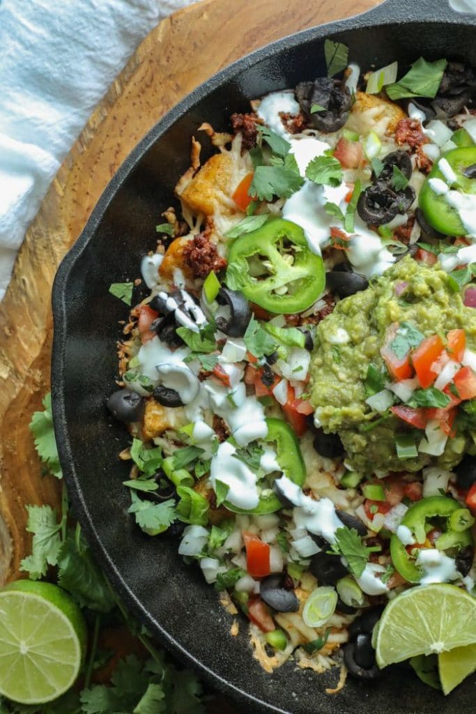 Easy Cauliflower Gnocchi Nachos in a cast iron skillet on a brown board.