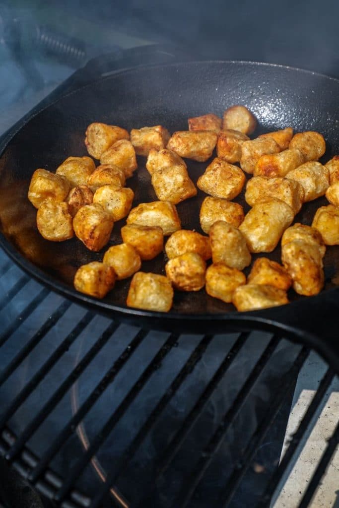 Cauliflower gnocchi being crisped on a cast iron on the big green egg grill.