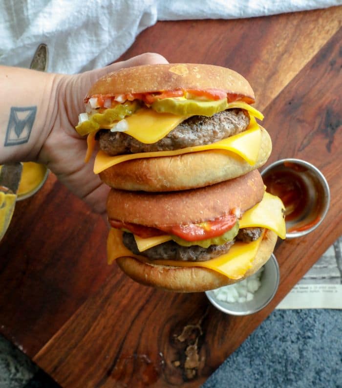 A hand holding two homemade keto quarter pounders.