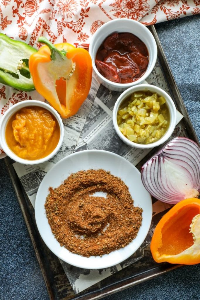 Peppers, chiles, spices, onion, and pumpkin in a bowl.