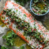 Butter Basted Slow Roasted Salmon with chimichurri over it on parchment paper