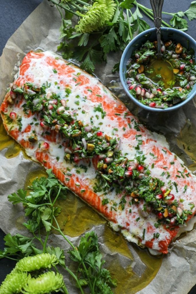 Butter Basted Slow Roasted Salmon with chimichurri over it on parchment paper