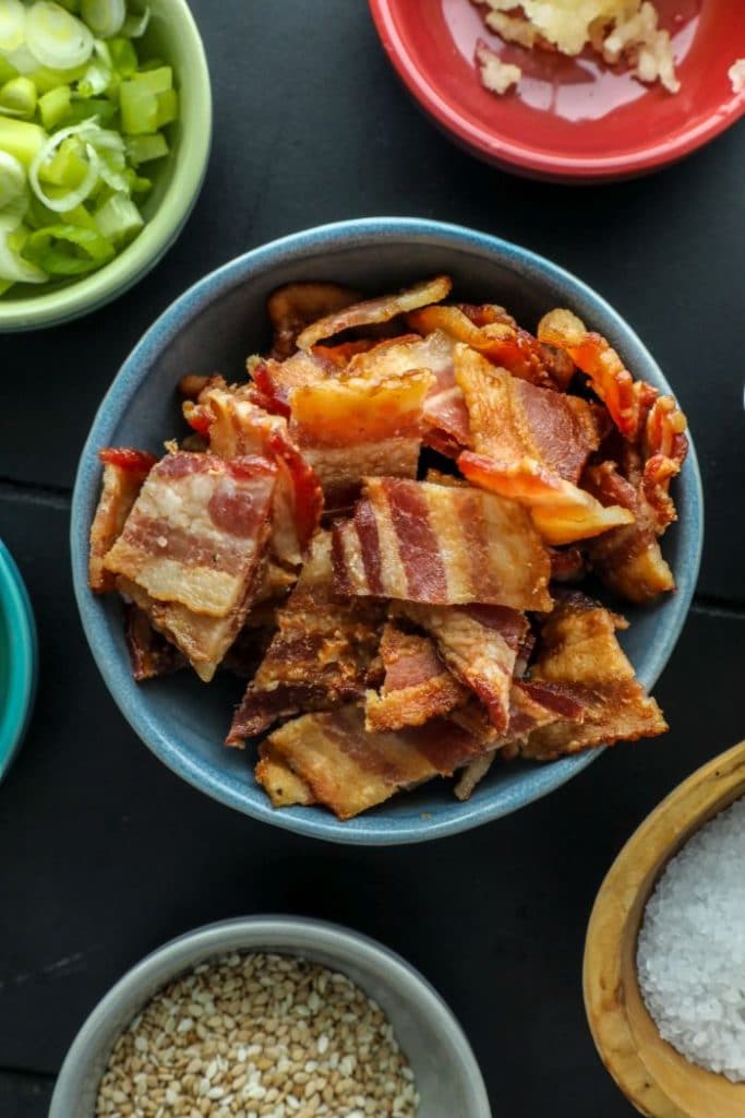 Cooked bacon pieces in a small blue bowl. 