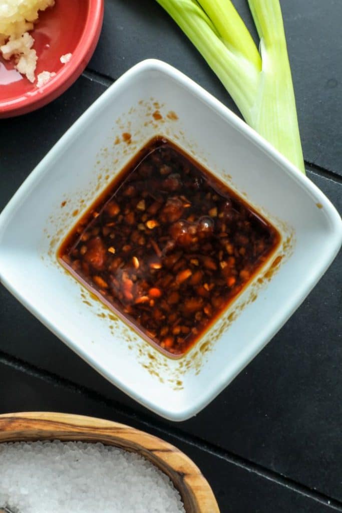 Chili paste and soy sauce mixed in a whitel bowl for the bacon cauliflower fried rice. 